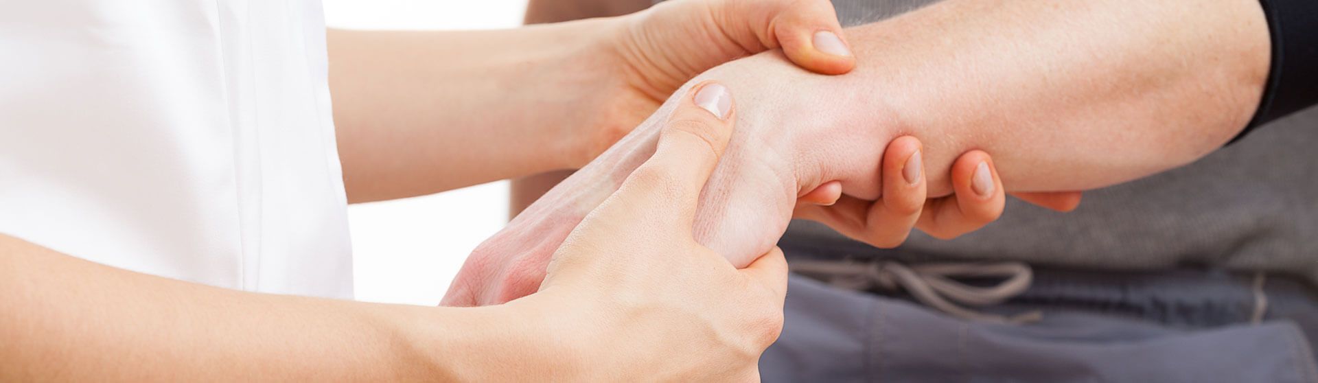 Ergotherapeutin behandelt die Hand eines Patienten.