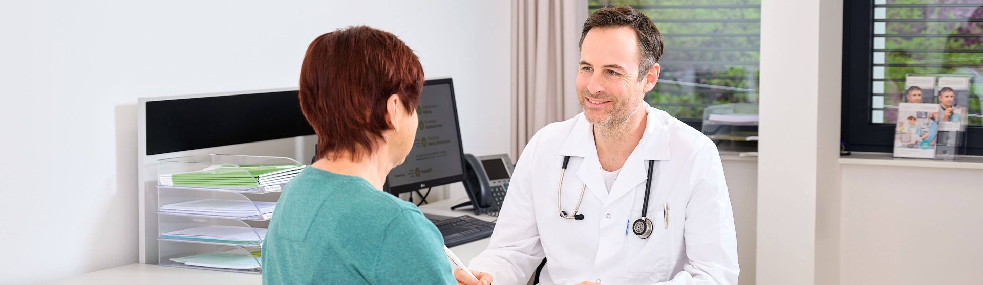 Arzt führt mit einer Patientin ein Gespräch im Gesundheitszentrum für Selbständige.
