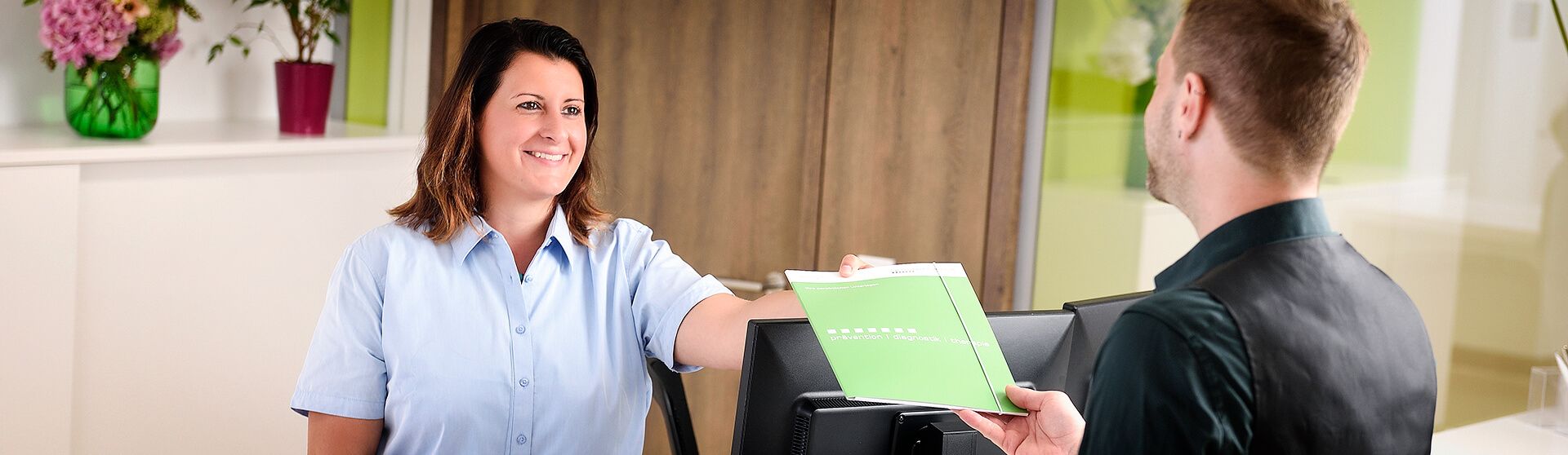 Patient meldet sich an der Leitstelle im Gesundheitszentrum an.