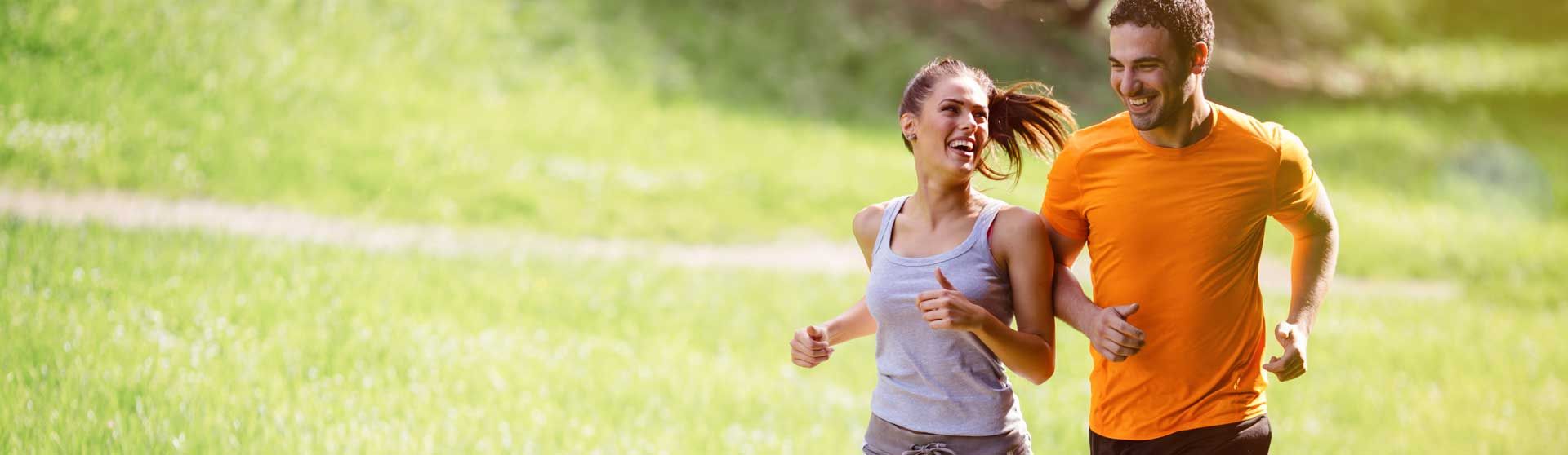 Junges Paar beim Joggen auf grüner Wiese.