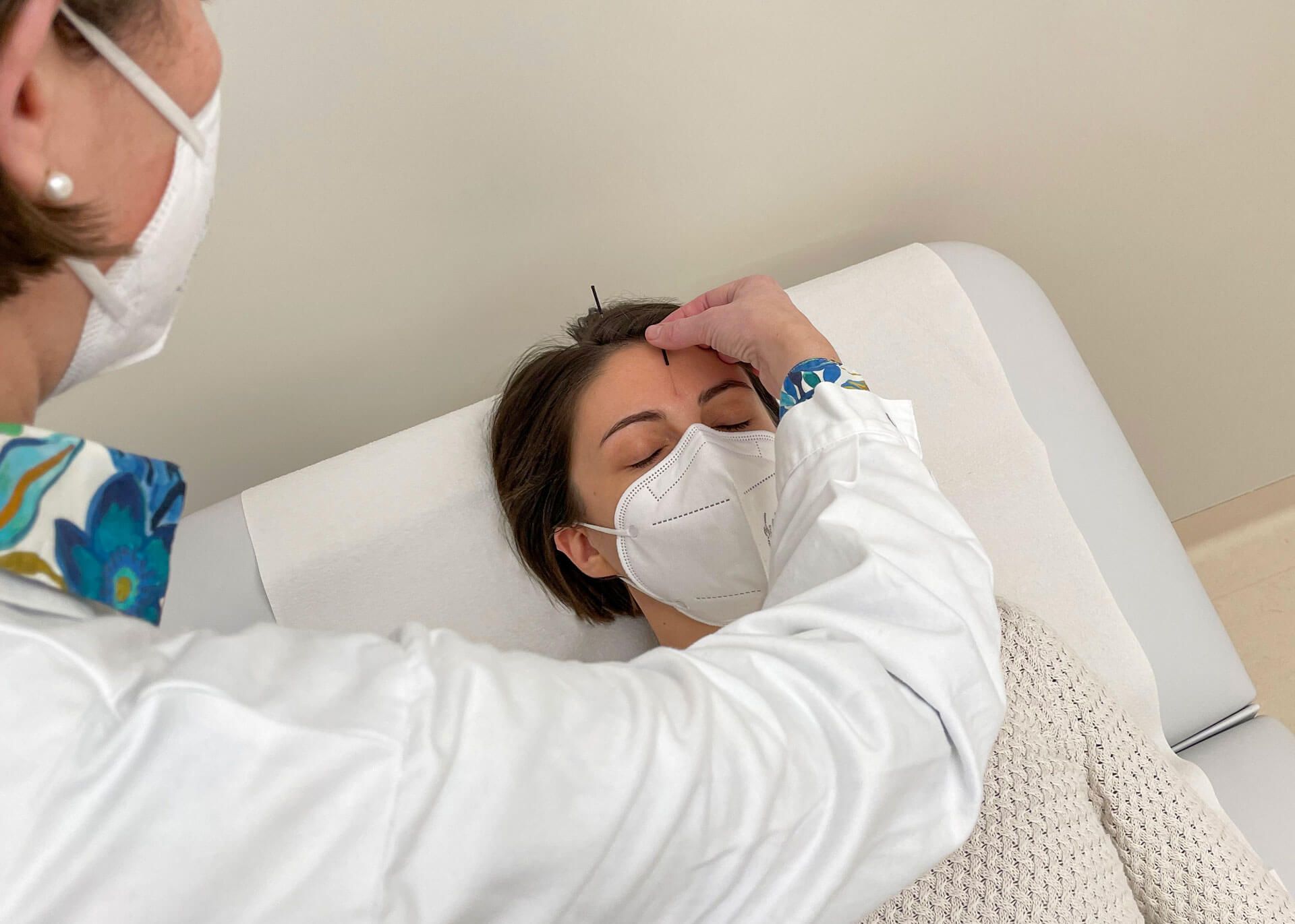 Patientin bekommt von einer Ärztin eine Akupunktur.