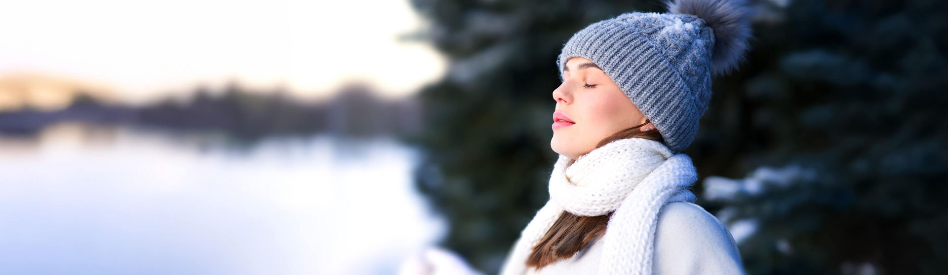 Frau steht im Freien und atmet kalte Winterluft ein.