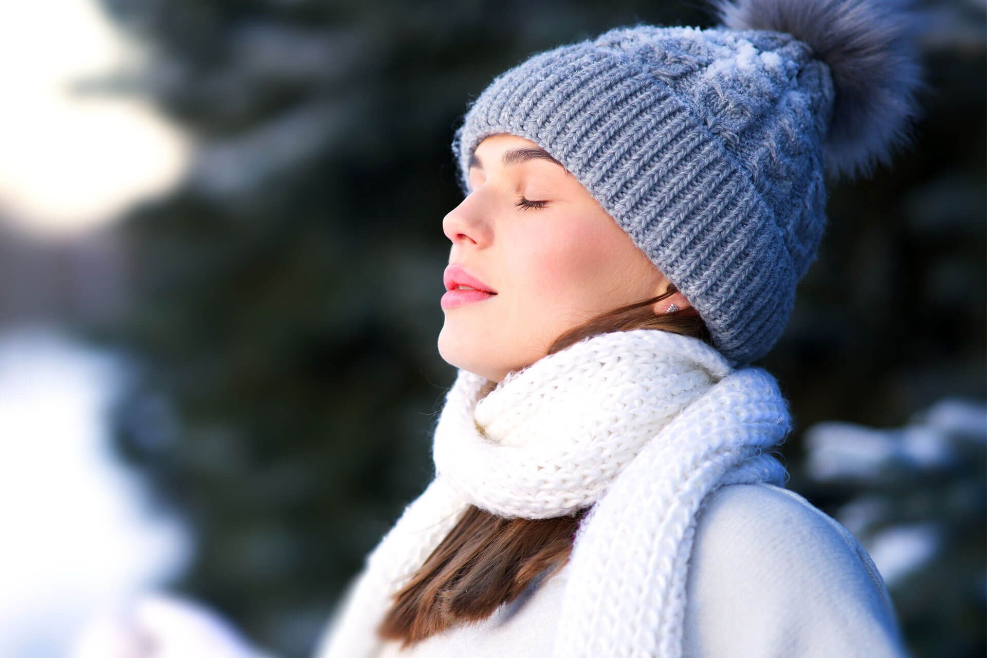 Frau steht im Freien und atmet kalte Winterluft ein.