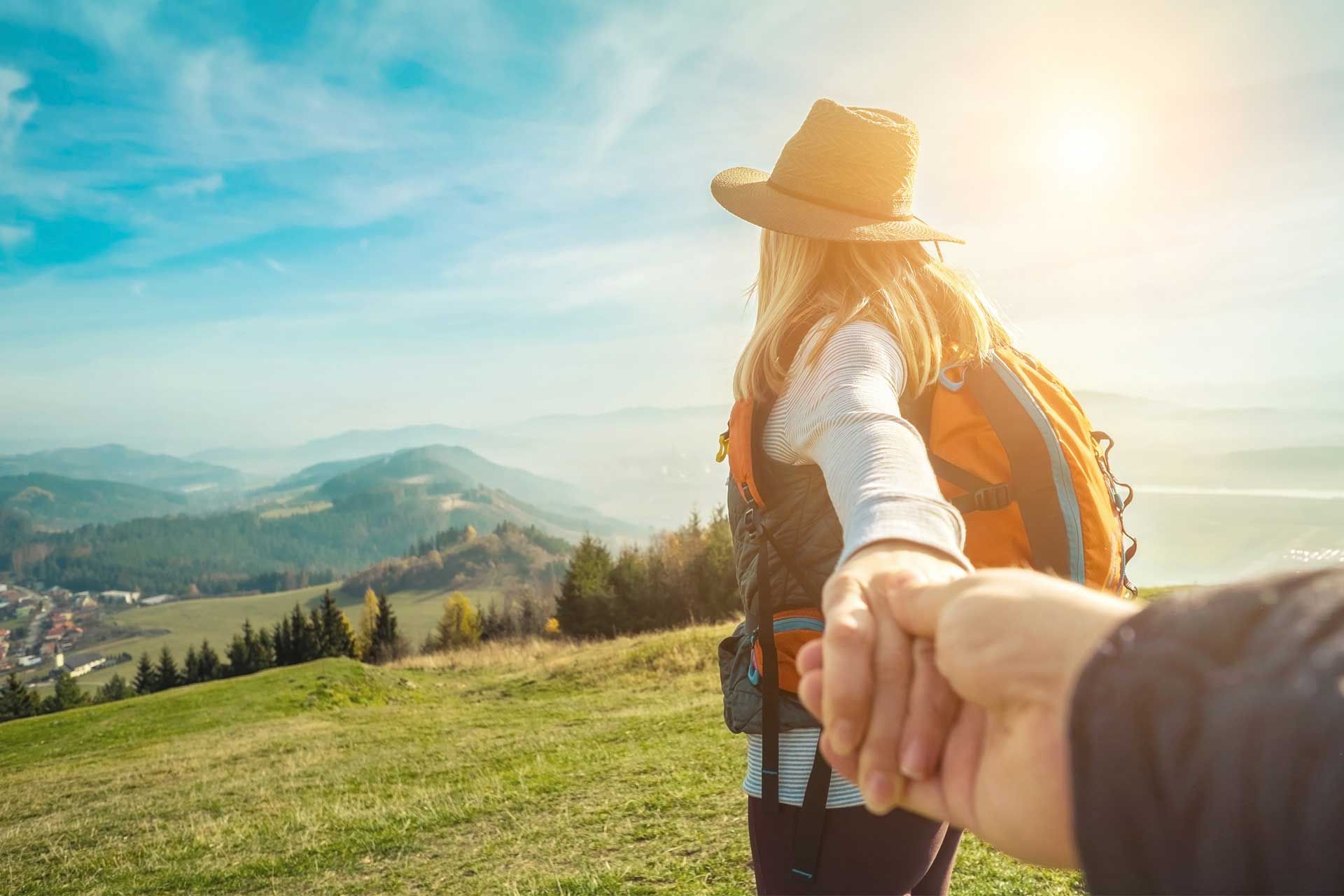 Frau blickt vom Berg ins Tal und hält die Hand ihres Mannes.