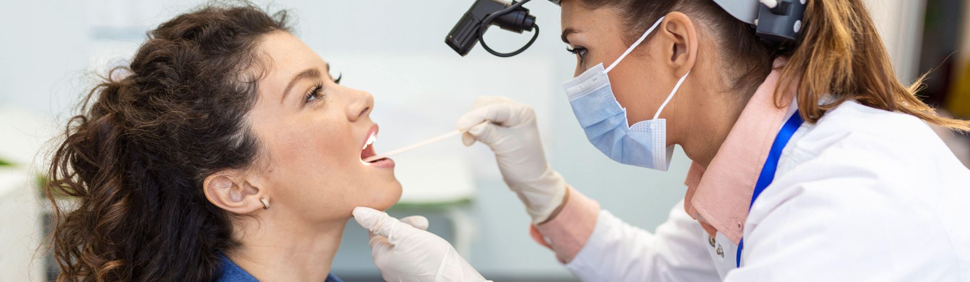 HNO-Ärztin untersucht den Hals einer Patientin.