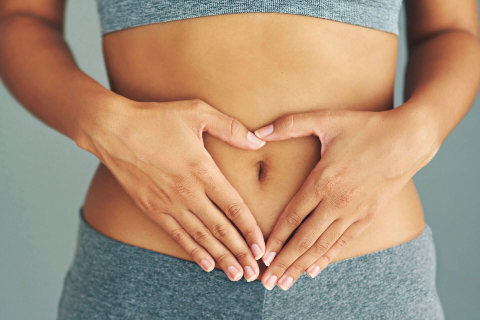 Frau hält die Hände vor den Bauch.