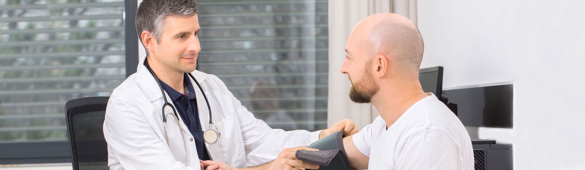 Arzt misst den Blutdruck eines Patienten.