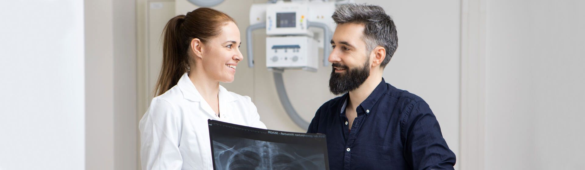 Radiologin erklärt einem Patienten eine Röntgenaufnahme.
