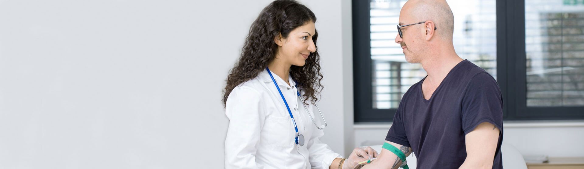 Ärztin führt am Patienten einen Blutabnahme durch.