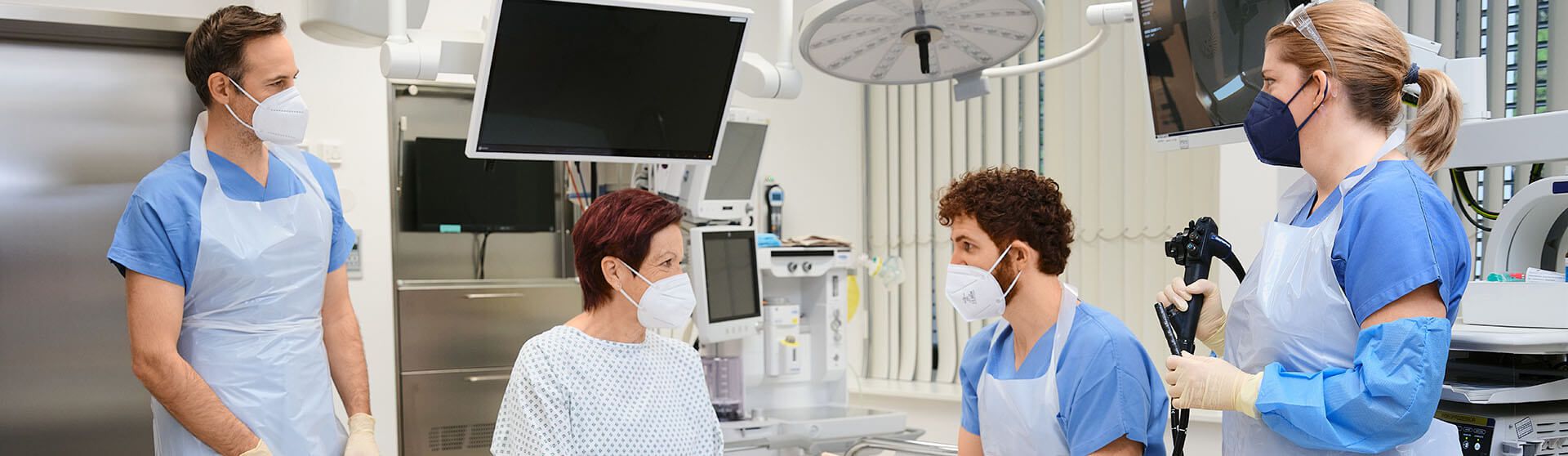 Patientin und Pflegekräfte führen vor der Endoskopie ein Gespräch.
