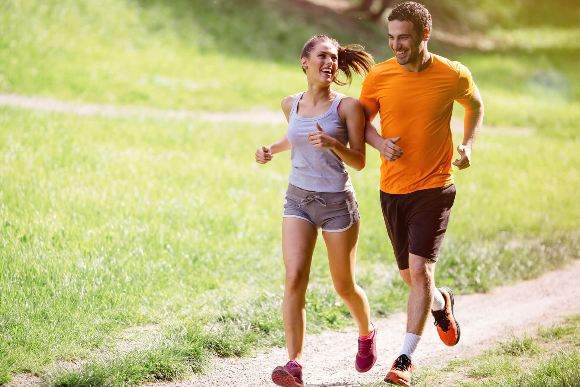 Junges Paar beim Joggen auf grüner Wiese.