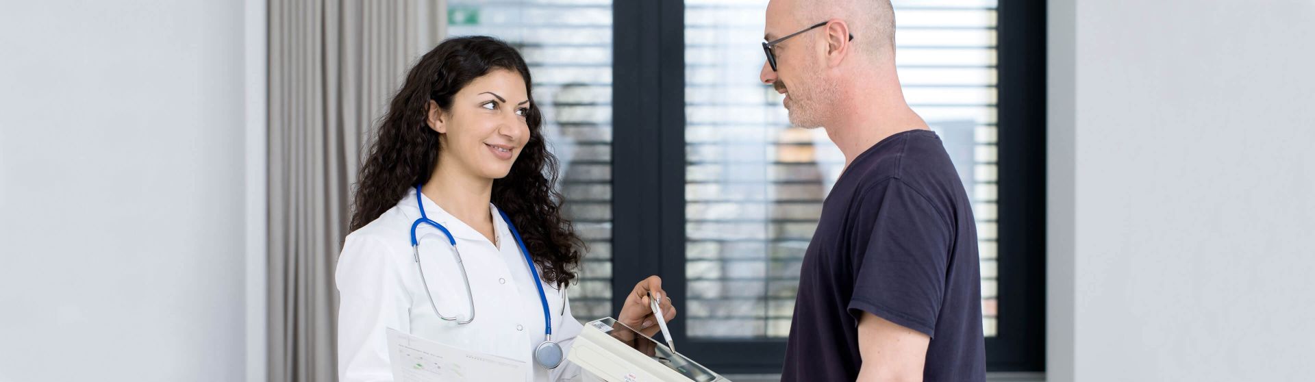 Patient steht auf der Waage, Ärztin liest das Gewicht ab.