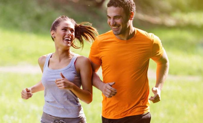 Junges Paar beim Joggen auf grüner Wiese.
