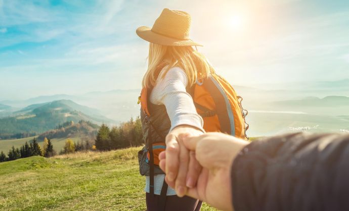 Frau blickt vom Berg ins Tal und hält die Hand ihres Mannes.